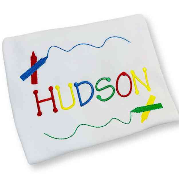 White fabric with colorful embroidered name 'Hudson' and stationery items on a white background