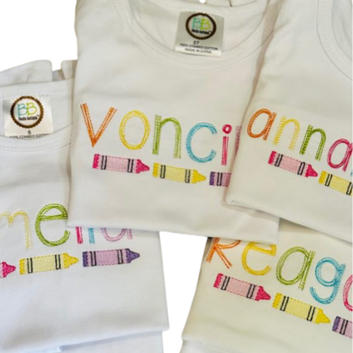 White shirts with colorful embroidered names and crayon designs on a white background