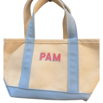 Beige tote bag with blue straps and 'PAM' monogram on a white background