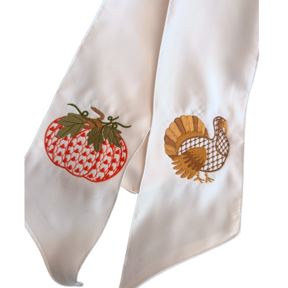 Two embroidered napkins with a pumpkin and a turkey on a white background