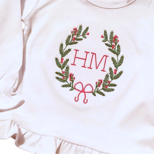 Embroidered design on a white garment with green leaves, red berries, and a pink bow.