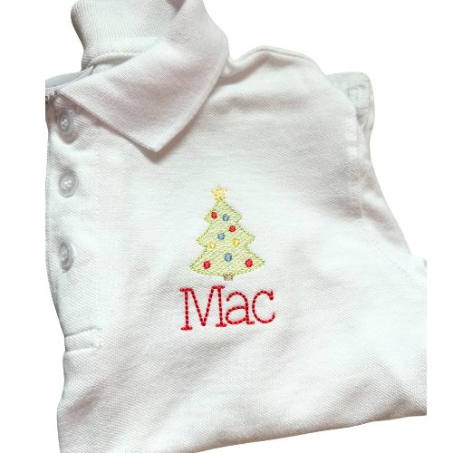 Folded white polo with embroidered Christmas tree and 'Mac' text on a white background