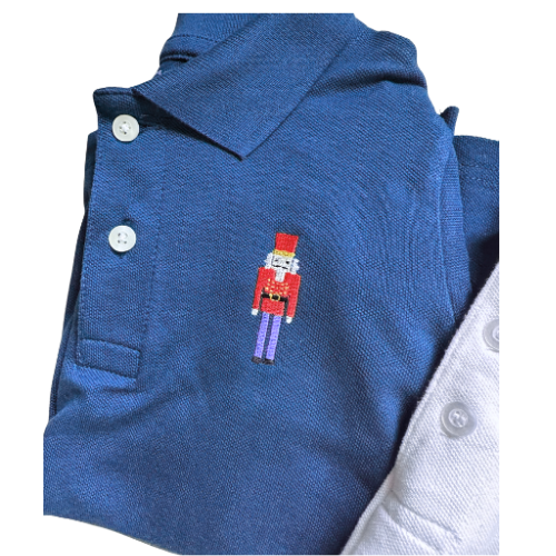 Blue polo shirt with a embroidered nutcracker design on a white background